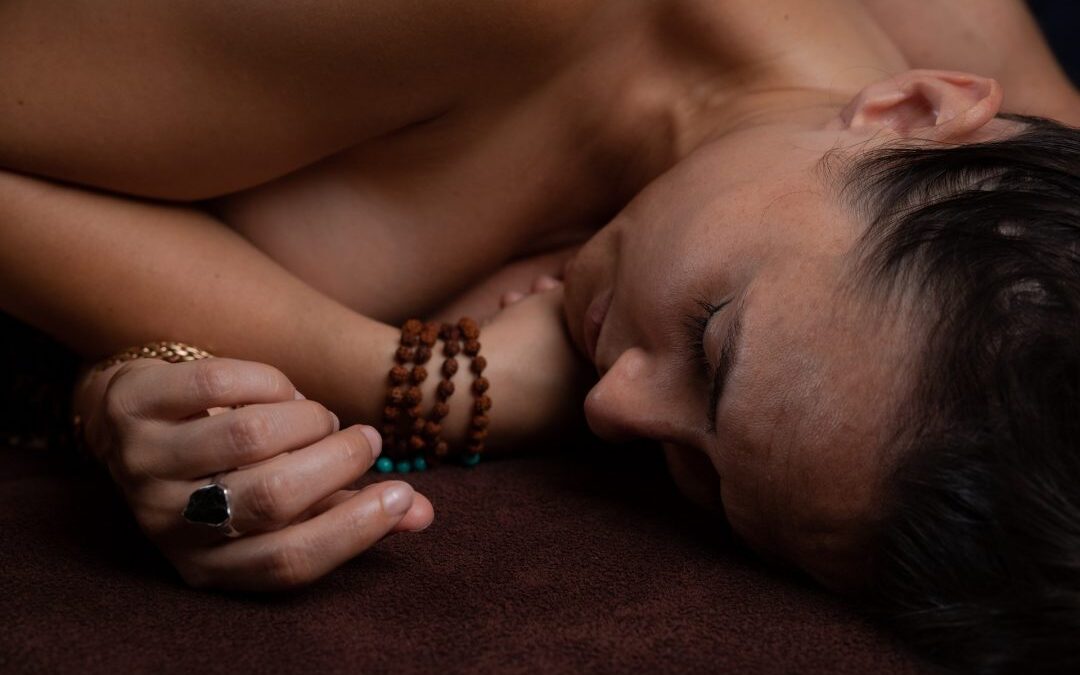 Kobieta leży na boku po masażu tantrycznym, widać tylko głowę i ręce.