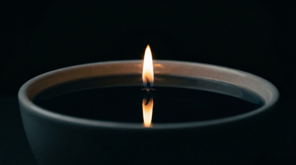Płomień świecy odbijający się w spokojnej tafli wosku, oleju, symbolika życia i świadomości, minimalistyczna kompozycja